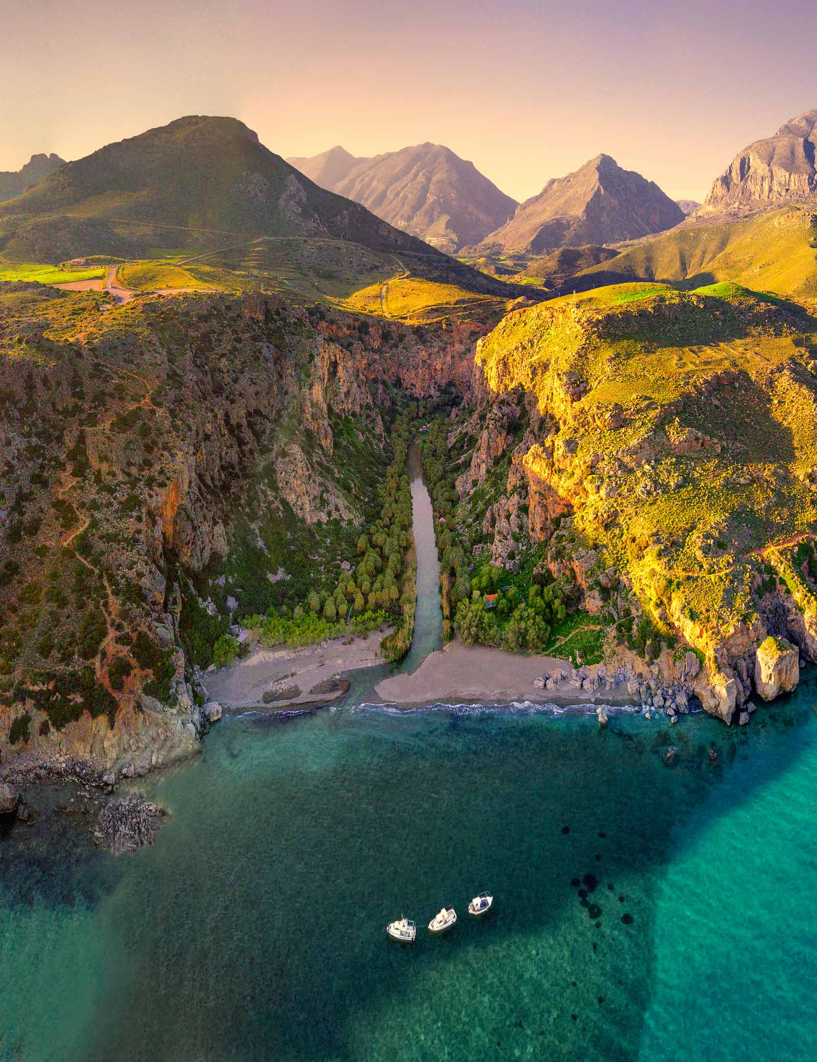 Preveli beach panoramic view, boats sailing by the river flowing to the sea